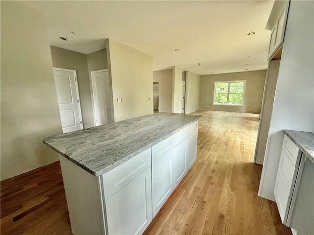 94 Ashaway Rd, Westerly, RI 02891 - kitchen featuring light wood-style flooring, a kitchen island, white cabinets, and light stone countertops