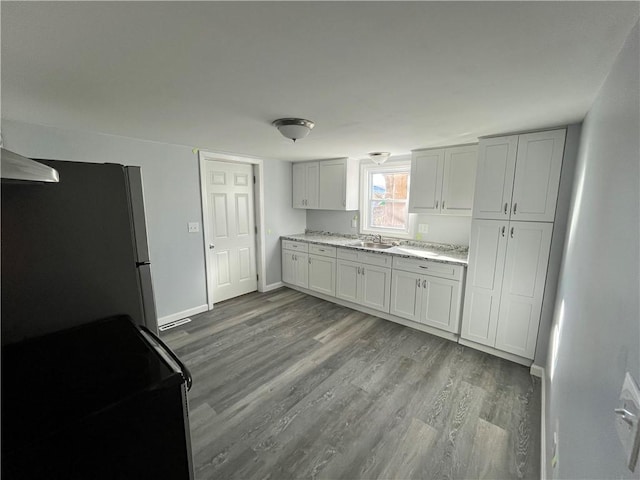 22 Agnes St, West Warwick, RI 02893 - kitchen featuring black range with electric stovetop, freestanding refrigerator, wood finished floors, and light stone countertops