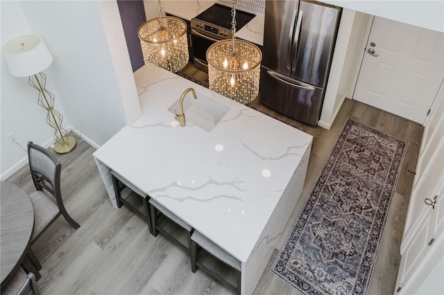 1000 Providence Pl Unit 467, Providence, RI 02903 - detailed view of freestanding refrigerator, light wood-type flooring, a chandelier, and light stone counters