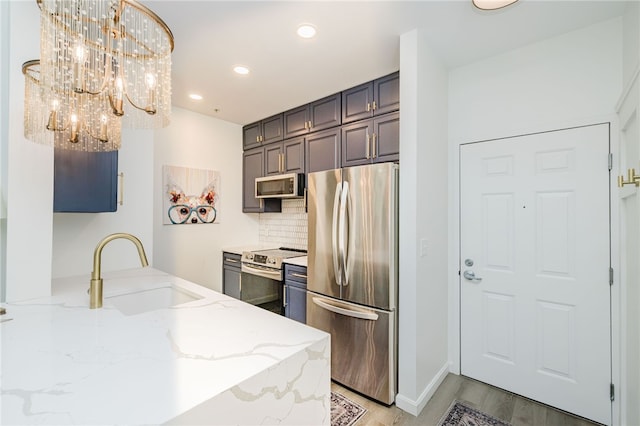 1000 Providence Pl Unit 467, Providence, RI 02903 - kitchen featuring appliances with stainless steel finishes, light stone counters, backsplash, a chandelier, and recessed lighting