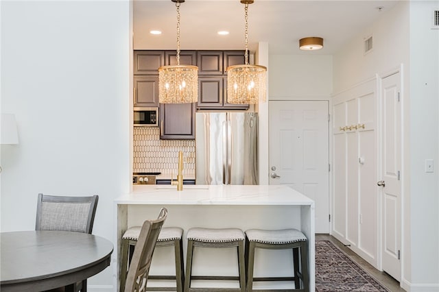 1000 Providence Pl Unit 467, Providence, RI 02903 - kitchen featuring appliances with stainless steel finishes, backsplash, a kitchen bar, a peninsula, and hanging light fixtures