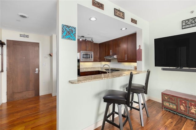 1 W Exchange St Unit 2802, Providence, RI 02903 - kitchen featuring stainless steel appliances, under cabinet range hood, wood finished floors, a breakfast bar, and light stone countertops