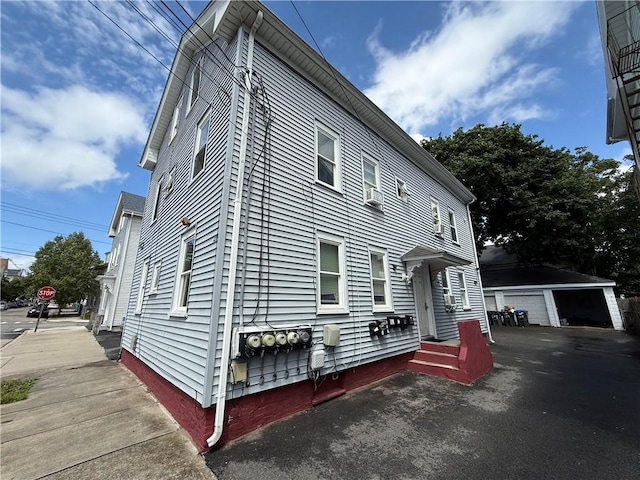 139 Julian St, Providence, RI 02909 - view of side of home with an outdoor structure, a detached garage, and cooling unit