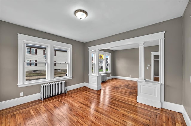 15 Melissa St, Providence, RI 02909 - empty room featuring radiator, decorative columns, and hardwood / wood-style flooring
