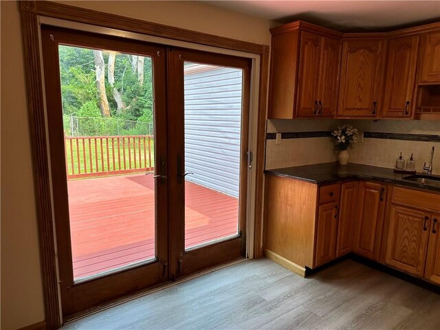 55 Circle Dr, Mansfield, CT 06250 - kitchen with french doors, light wood finished floors, backsplash, dark countertops, and brown cabinets
