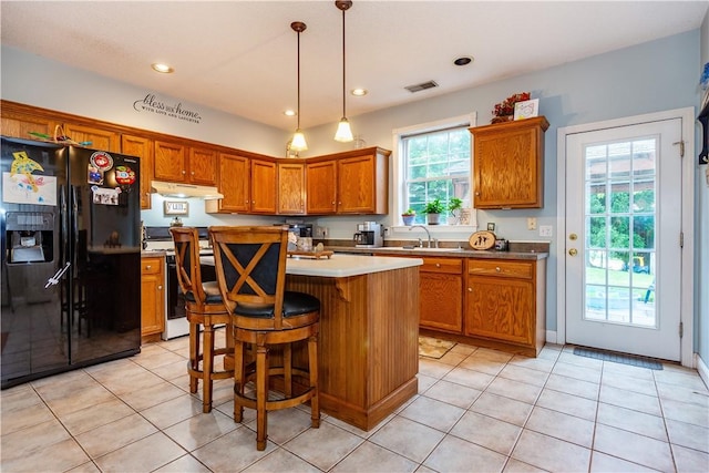 50 S Pond Dr, Coventry, RI 02816 - kitchen with black fridge with ice dispenser, white electric range, under cabinet range hood, brown cabinetry, and light tile patterned floors