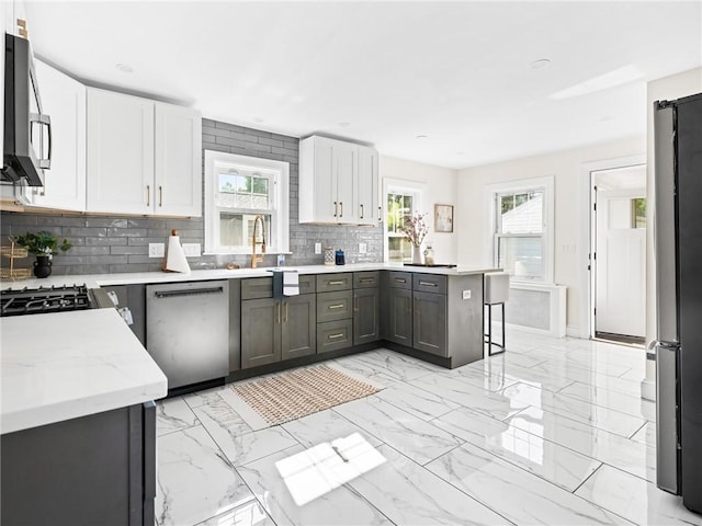 155 Hillside Ave, Providence, RI 02906 - kitchen with stainless steel appliances, decorative backsplash, a peninsula, and white cabinets