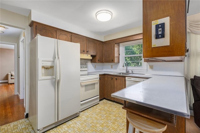 185 Sunnybrook Dr, North Kingstown, RI 02852 - kitchen featuring white appliances, light countertops, under cabinet range hood, a breakfast bar area, and brown cabinets
