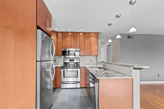 76 Valley Green Ct Unit B, North Providence, RI 02904 - kitchen with appliances with stainless steel finishes, a peninsula, brown cabinets, and decorative backsplash