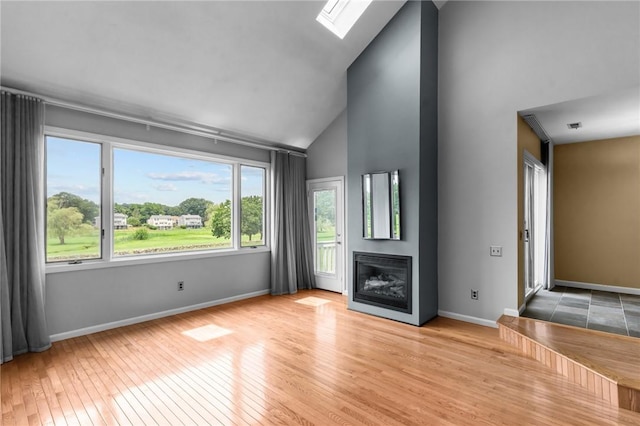 76 Valley Green Ct Unit B, North Providence, RI 02904 - unfurnished living room featuring a glass covered fireplace, hardwood / wood-style flooring, a skylight, and high vaulted ceiling