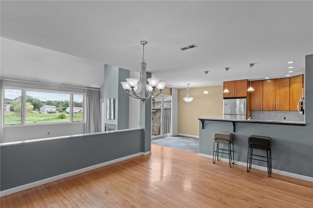 76 Valley Green Ct Unit B, North Providence, RI 02904 - kitchen featuring freestanding refrigerator, a chandelier, brown cabinetry, light wood-style flooring, and a kitchen bar