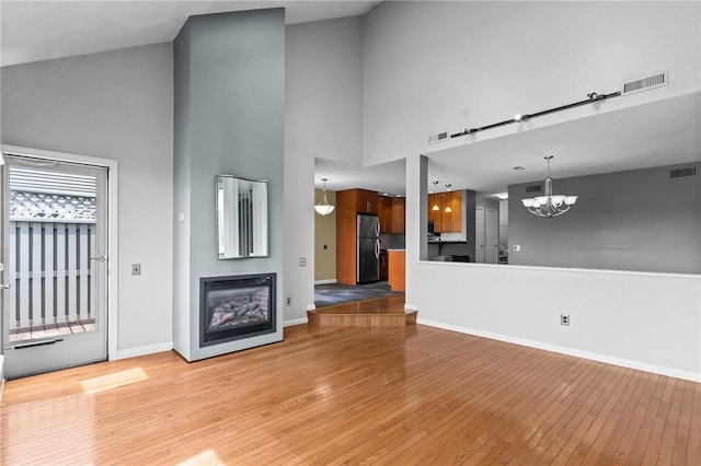 76 Valley Green Ct Unit B, North Providence, RI 02904 - unfurnished living room with a chandelier, light wood-style floors, a high ceiling, and a glass covered fireplace