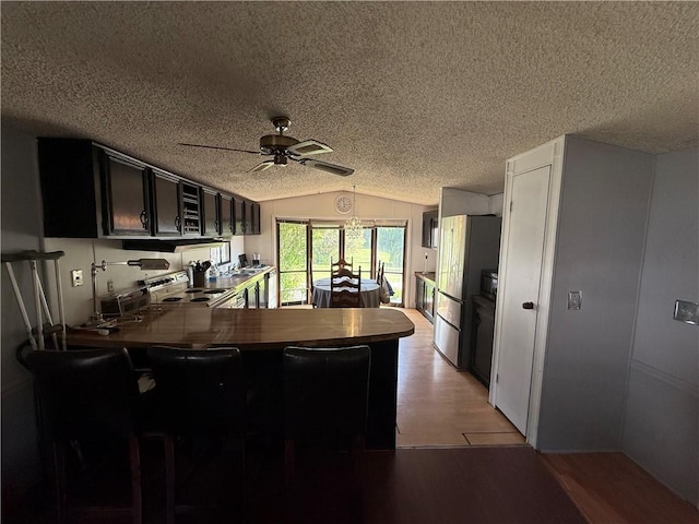 225 Brayton Ave, Tiverton, RI 02878 - kitchen with vaulted ceiling, freestanding refrigerator, a peninsula, a ceiling fan, and a textured ceiling