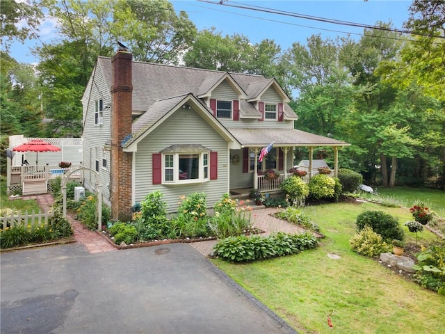 50 Betony Rd, Narragansett, RI 02874 - view of front of house featuring covered porch, a front lawn, a shingled roof, and a chimney