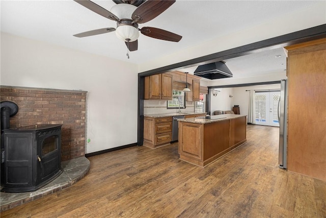 50 Betony Rd, Narragansett, RI 02874 - kitchen with stainless steel appliances, brown cabinets, a kitchen island, a wood stove, and dark wood-type flooring
