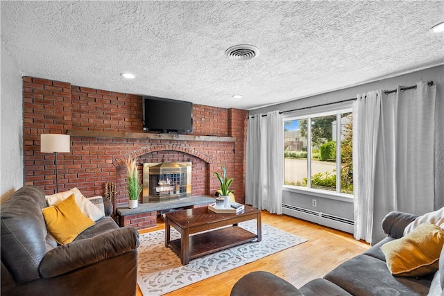 59 Columbus Ave, North Providence, RI 02911 - living area with a baseboard heating unit, wood finished floors, a textured ceiling, a brick fireplace, and recessed lighting