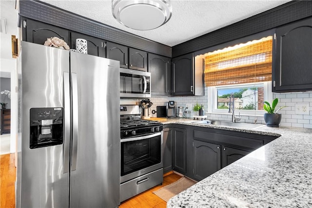 59 Columbus Ave, North Providence, RI 02911 - kitchen with stainless steel appliances, tasteful backsplash, light stone counters, light wood finished floors, and a textured ceiling