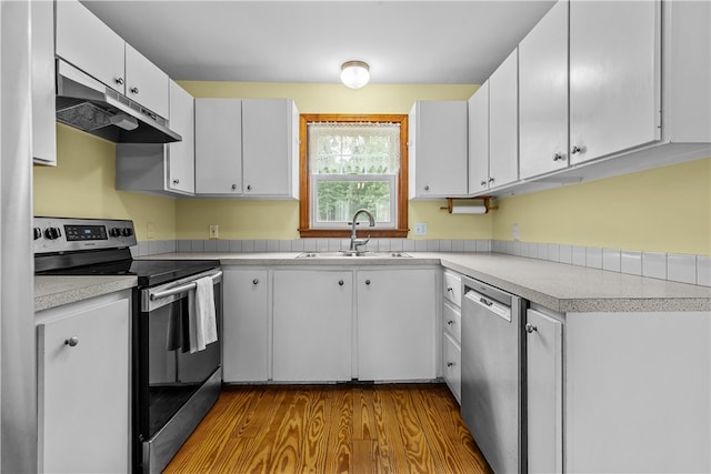 140 Long Hwy, Little Compton, RI 02837 - kitchen with stainless steel appliances, under cabinet range hood, light countertops, wood finished floors, and white cabinetry