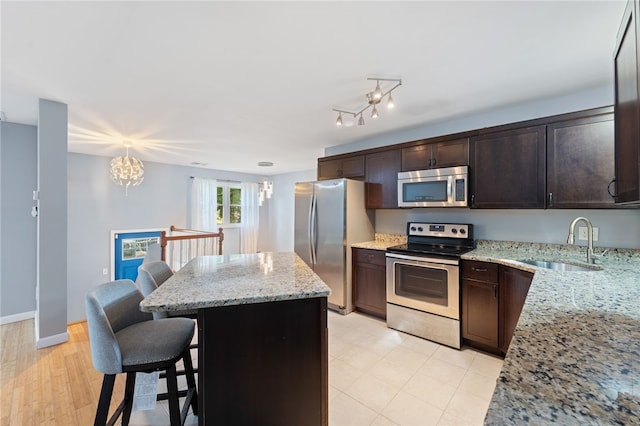 22 Riverdale Rd, Westerly, RI 02891 - kitchen featuring stainless steel appliances, a center island, dark brown cabinetry, light stone counters, and a chandelier