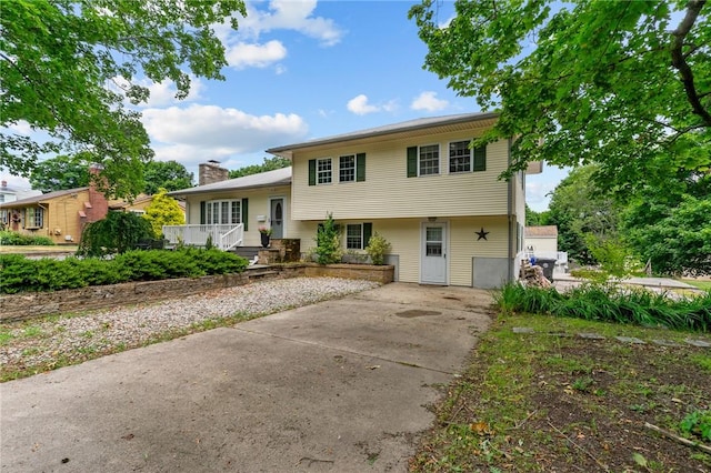 203 Pulaski St, West Warwick, RI 02893 - view of front of house with concrete driveway, a chimney, and a wooden deck