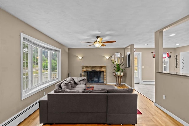 203 Pulaski St, West Warwick, RI 02893 - living room with a baseboard radiator, ceiling fan, a stone fireplace, light wood-style floors, and recessed lighting