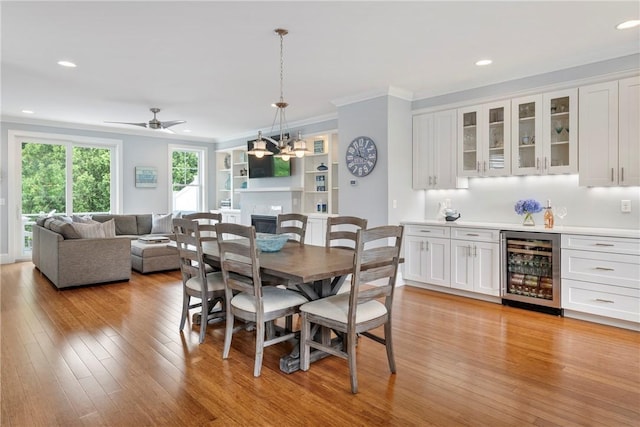 100 Algonquin Rd Unit 13, Narragansett, RI 02882 - dining area with beverage cooler, crown molding, light wood finished floors, recessed lighting, and a glass covered fireplace