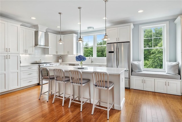 100 Algonquin Rd Unit 13, Narragansett, RI 02882 - kitchen featuring stainless steel appliances, wall chimney range hood, a center island, white cabinetry, and light countertops