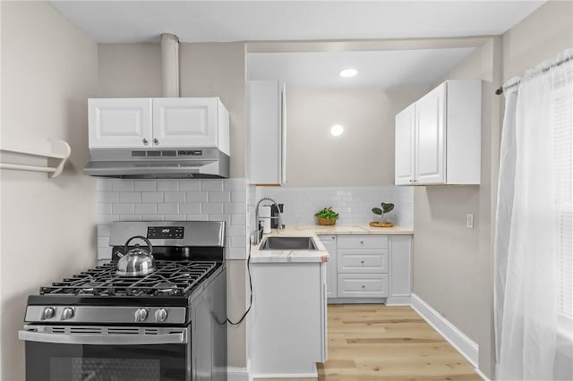 1413 Broad St, Providence, RI 02905 - kitchen featuring stainless steel gas range, under cabinet range hood, light wood-style flooring, white cabinets, and light countertops