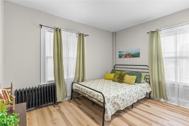 1413 Broad St, Providence, RI 02905 - bedroom featuring radiator heating unit, wood finished floors, and multiple windows