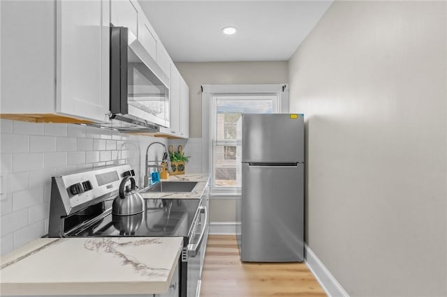 1413 Broad St, Providence, RI 02905 - kitchen featuring appliances with stainless steel finishes, white cabinets, backsplash, light wood-style flooring, and recessed lighting