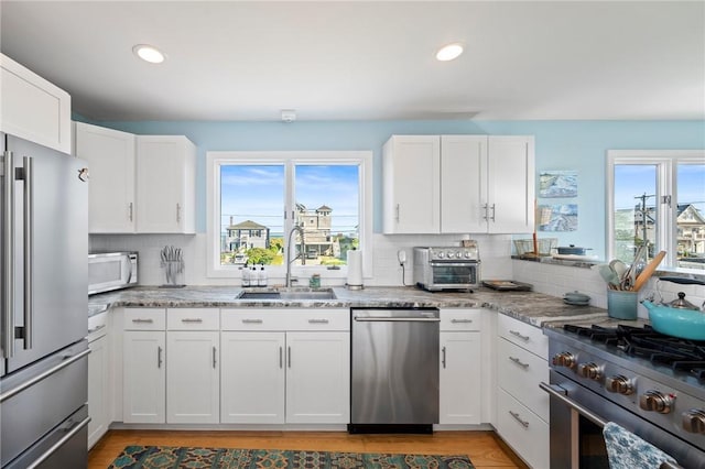 408 Atlantic Ave, Westerly, RI 02891 - kitchen with high quality appliances, healthy amount of natural light, backsplash, white cabinetry, and recessed lighting