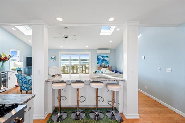 408 Atlantic Ave, Westerly, RI 02891 - kitchen featuring a skylight, a wall mounted air conditioner, a ceiling fan, a breakfast bar area, and recessed lighting