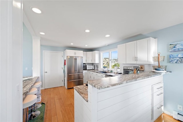 408 Atlantic Ave, Westerly, RI 02891 - kitchen featuring freestanding refrigerator, baseboard heating, light wood finished floors, white cabinetry, and recessed lighting