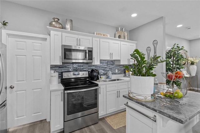 406 Cahill St, Providence, RI 02905 - kitchen with appliances with stainless steel finishes, light wood-type flooring, white cabinets, backsplash, and recessed lighting