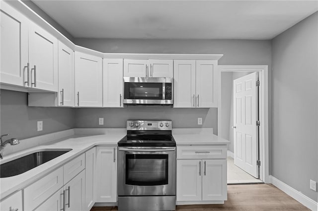 406 Cahill St, Providence, RI 02905 - kitchen with appliances with stainless steel finishes, white cabinetry, light countertops, and wood finished floors