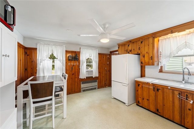 2 Glen Dr, Warwick, RI 02889 - kitchen with freestanding refrigerator, radiator heating unit, brown cabinetry, light countertops, and a ceiling fan