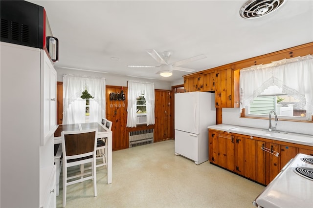 2 Glen Dr, Warwick, RI 02889 - kitchen with white appliances, radiator heating unit, brown cabinetry, a ceiling fan, and light countertops