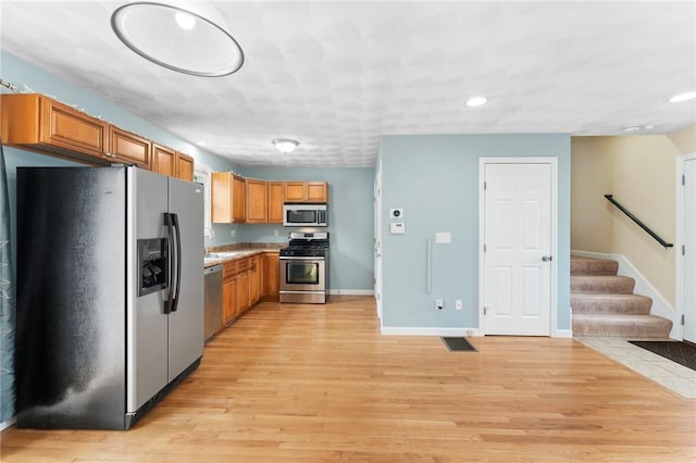 174 Long St, Warwick, RI 02886 - kitchen with appliances with stainless steel finishes, recessed lighting, brown cabinetry, light wood finished floors, and light countertops