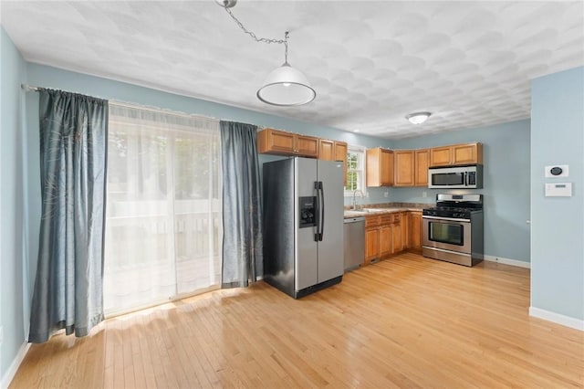 174 Long St, Warwick, RI 02886 - kitchen with stainless steel appliances, light wood-style flooring, brown cabinetry, pendant lighting, and light countertops