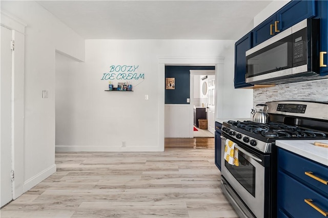 61 Wealth Ave, Providence, RI 02908 - kitchen with appliances with stainless steel finishes, blue cabinetry, light wood-type flooring, light countertops, and a wainscoted wall