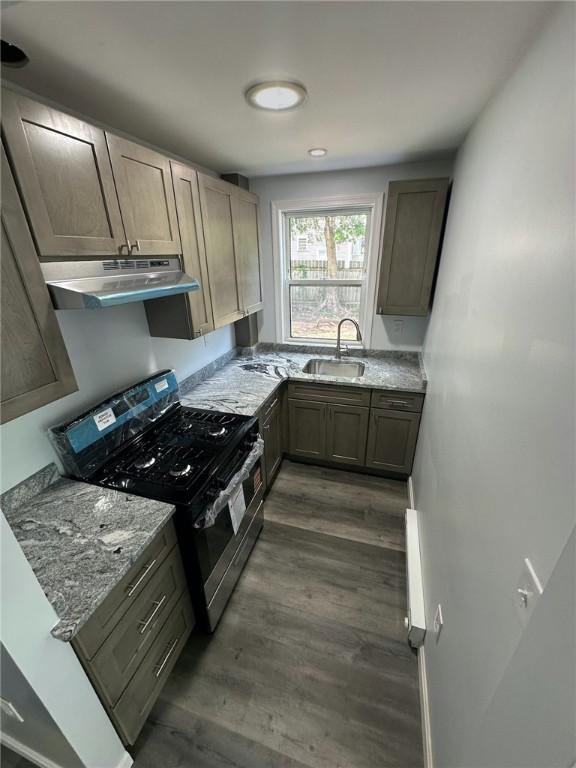 208 Carnation St, Pawtucket, RI 02860 - kitchen with stainless steel range with gas cooktop, under cabinet range hood, dark wood-style floors, and light stone counters