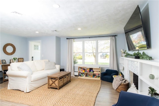 94 Osage Dr, Warwick, RI 02888 - living area with a fireplace, wood finished floors, baseboard heating, and recessed lighting