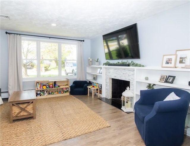 94 Osage Dr, Warwick, RI 02888 - living area with wood finished floors, a stone fireplace, and baseboard heating