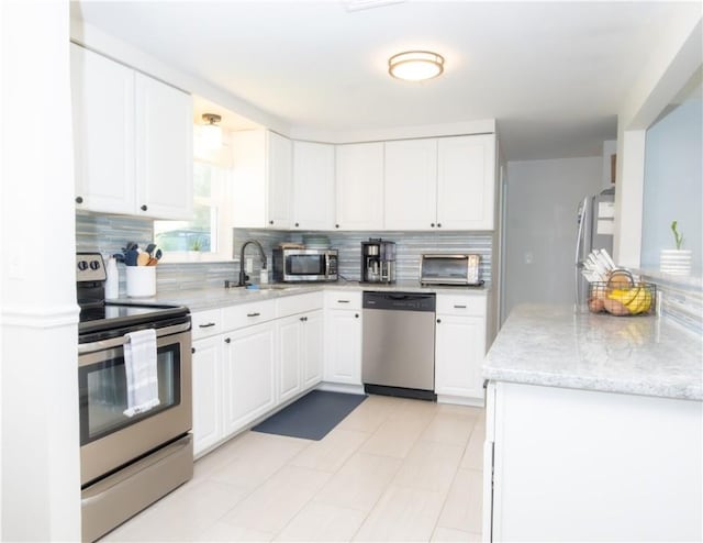 94 Osage Dr, Warwick, RI 02888 - kitchen with stainless steel appliances, backsplash, white cabinetry, and light stone counters