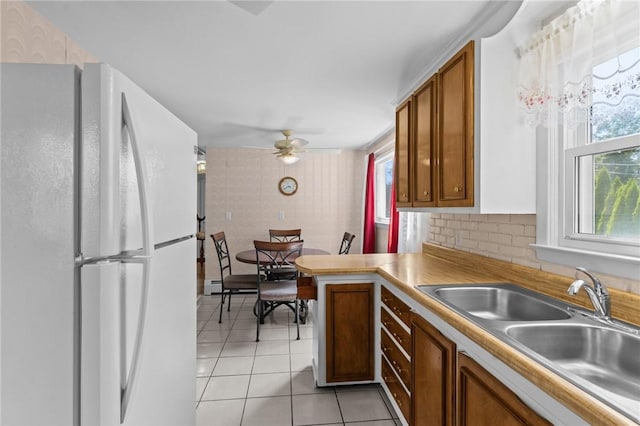 33 Limestone St, Warwick, RI 02889 - kitchen featuring freestanding refrigerator, light tile patterned floors, ceiling fan, brown cabinets, and a peninsula