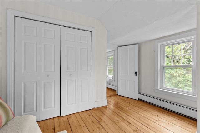 303 Washington Rd, Barrington, RI 02806 - unfurnished bedroom with baseboard heating, a baseboard radiator, light wood finished floors, and multiple windows