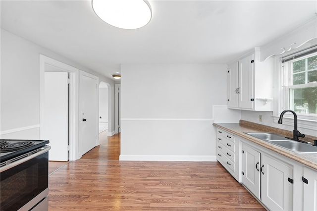 32 Rosemere Dr, East Providence, RI 02914 - kitchen with arched walkways, white cabinets, light wood-style floors, and stainless steel range with electric cooktop
