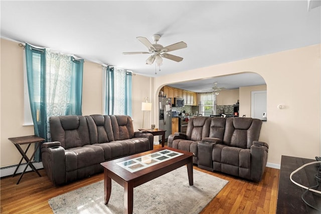 7 Snell Ct, West Warwick, RI 02893 - living room with arched walkways, ceiling fan, light wood-style flooring, and baseboard heating