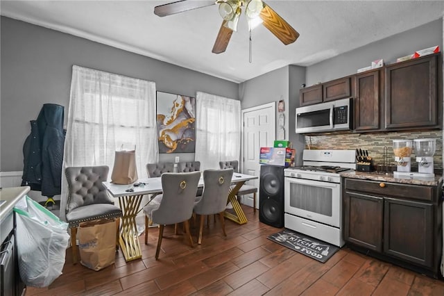 19 Covell St, Providence, RI 02909 - kitchen with stainless steel microwave, white gas range, backsplash, dark brown cabinets, and dark wood-style flooring