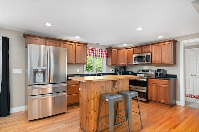 219 Fenner Hill Rd, Hopkinton, RI 02832 - kitchen with stainless steel appliances, a kitchen island, a breakfast bar area, light wood-style floors, and brown cabinetry